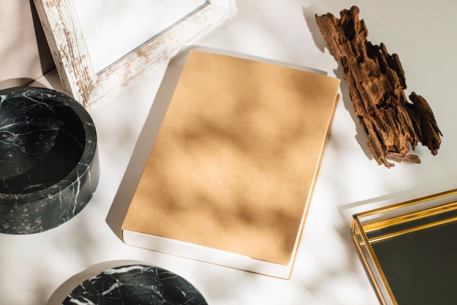 Elegant still life mockup featuring a brown book, marble bowl, and artistic shadows.